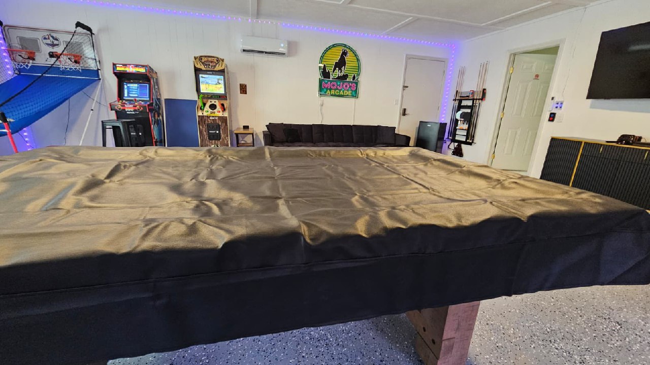 Pool table from behind with full arcade room view